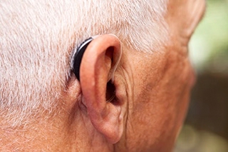 männlicher Hinterkopf mit Hörgerät am Ohr